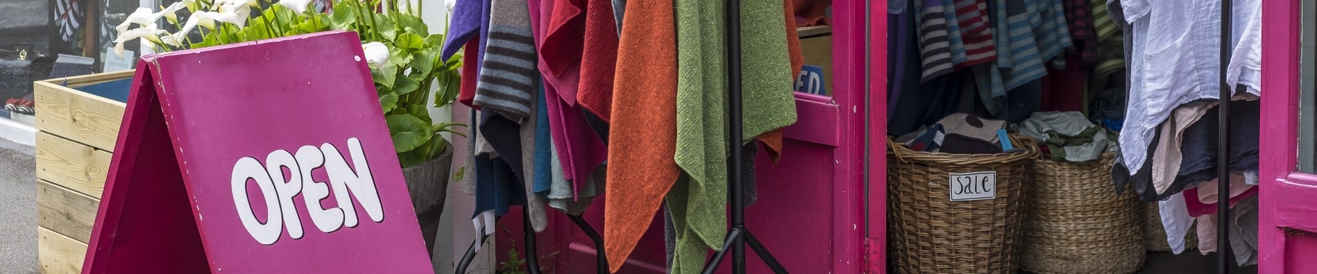 Brightly colored Open sign outside a shop selling clothes, on a sunny day in London, UK