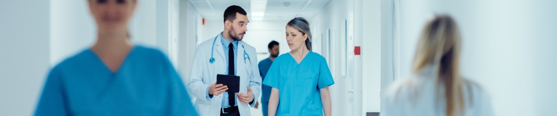 Surgeon and Female Doctor Walk Through Hospital