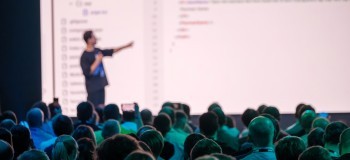 Presenter interacting with coding backdrop in front of a crowd