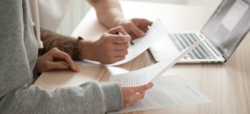 Couple reading legal documents at home with laptop