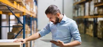 Man warehouse worker with a tablet 
