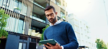 Man with tablet in front of apartment block