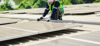 Person installing PV solar panels on a flat roof