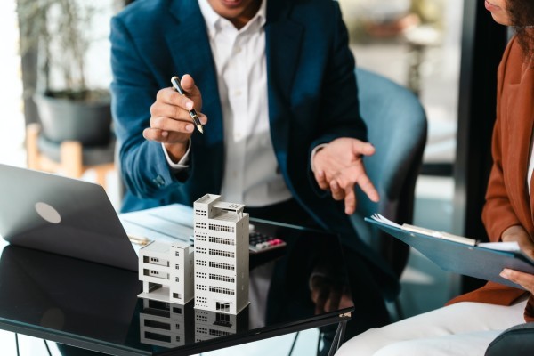 Attractive Asian businessman and African American female real estate and land investor talk discussing together on table with laptop and small building model  Reserve fund