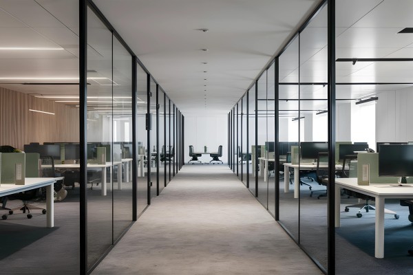 A modern workspace characterized by a sleek, minimalist design  The office showcases clean lines and an open layout, with glass partitions that create a sense of space and transparency 