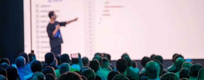 Presenter interacting with coding backdrop in front of a crowd