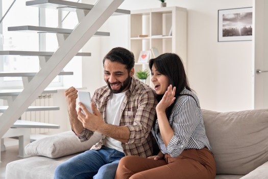 Family couple winners look at smart phone celebrate win