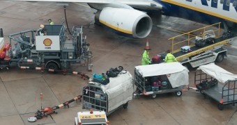 Ground staff at Manchester Airport refuel a Ryanair aircraft as passenger baggage is loaded