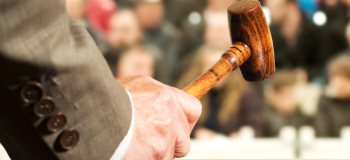 Auctioneer using gavel in the foreground with people in the background