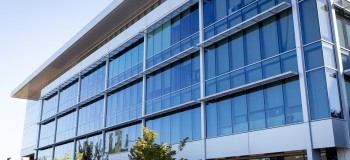 A modern contemporary office building with glass facade on a sunny day no people, clear blue sky