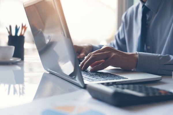 Business man or accountant working on laptop computer with business document graph diagram and calculator on office table scaled