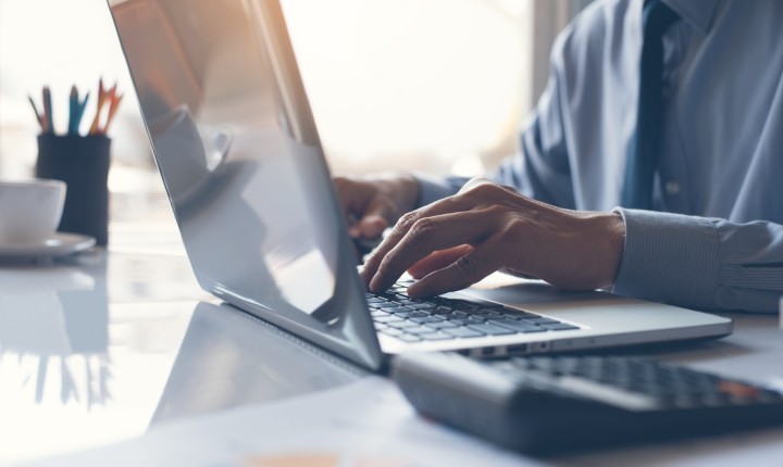 Business man or accountant working on laptop computer with business document graph diagram and calculator on office table scaled