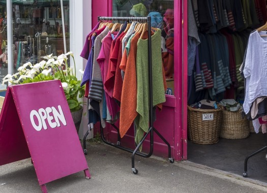 Brightly colored Open sign outside a shop selling clothes, on a sunny day in London, UK