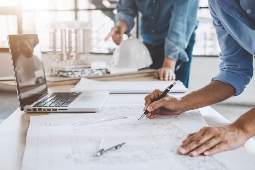 Construction concept of Engineer working with partner and engineering tools on model building and blueprint in working site