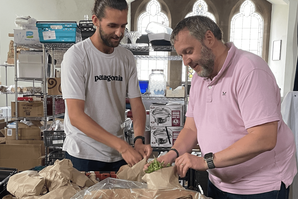 Reece Andrade, in a white Patagonia t-shirt, and Andrew Glover, in a pink polo shirt, bag up rocket for cookery classes at the Cooking Champions Community Kitchen